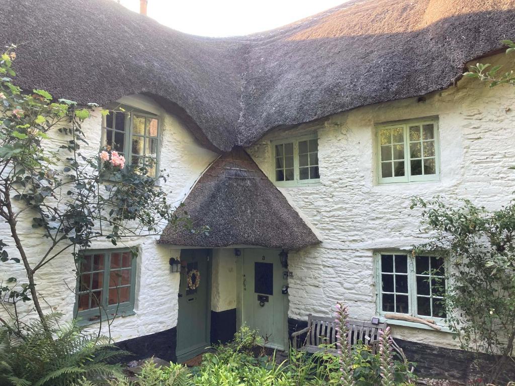 een oud wit huisje met een rieten dak bij 4 Cumberland Cottages in Kingsbridge