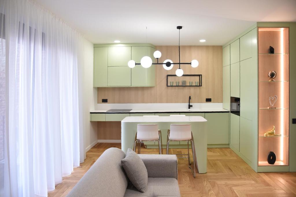 uma cozinha com armários verdes e uma mesa e cadeiras brancas em 26Bricks Luxury Suites em Oradea