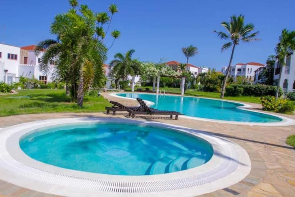 una gran piscina con dos bancos en un patio en The hayce residence, en Kilifi