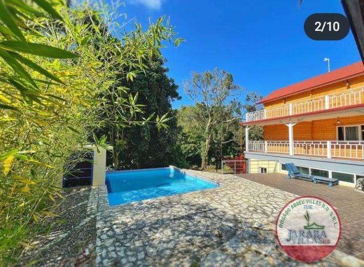 a swimming pool in front of a house at Villa encantadora pino alto J4 in Jarabacoa
