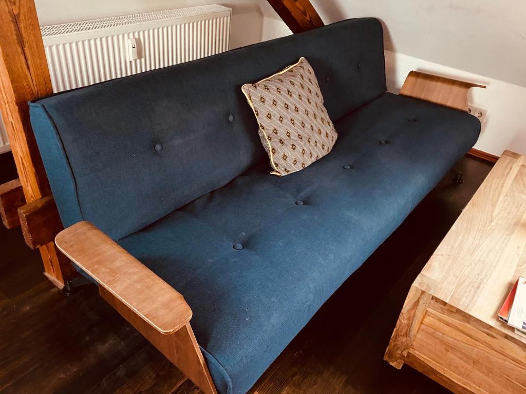 eine blaue Couch mit einem Kissen neben einem Tisch in der Unterkunft Moderne Wohnung im Grünen in Werneuchen