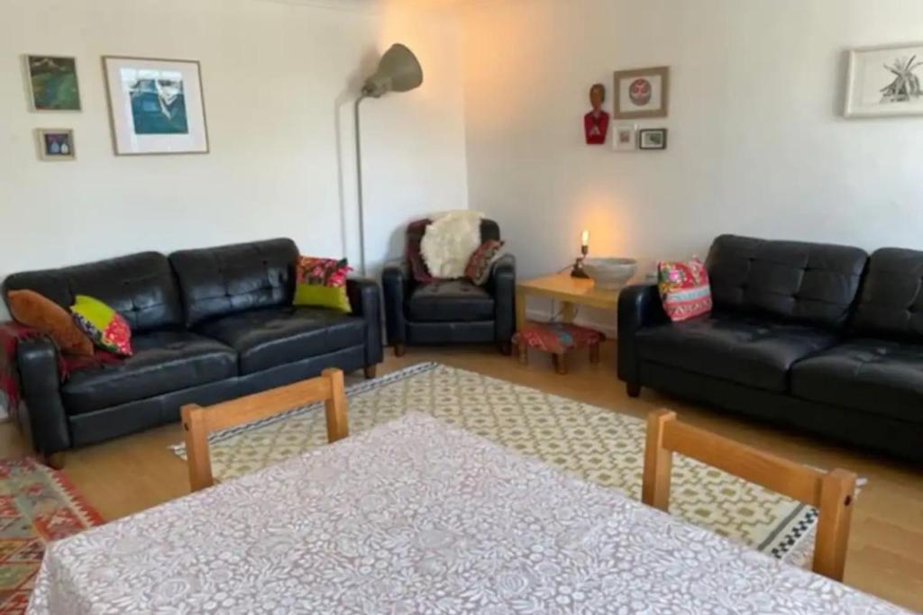 a living room with black couches and a table at Charming 3 Bedroom Apartment in the Heart of Vibrant Old Town in Edinburgh