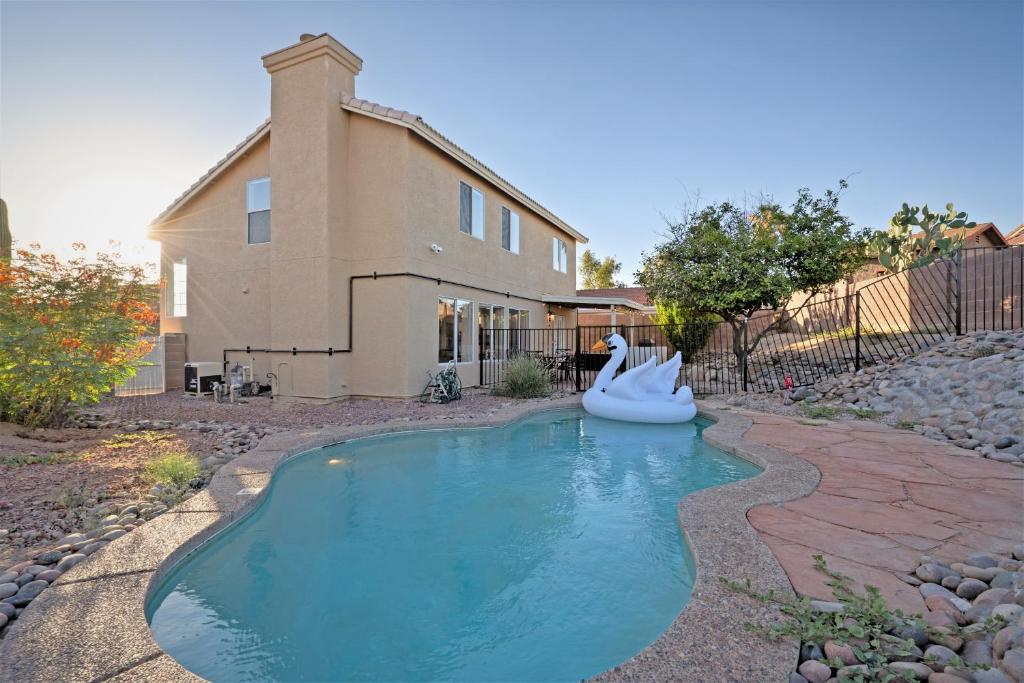 une piscine avec un cygne gonflable en face d'une maison dans l'établissement @ Marbella Lane - Elegant & Artistic Home w/ Pool, à Tucson