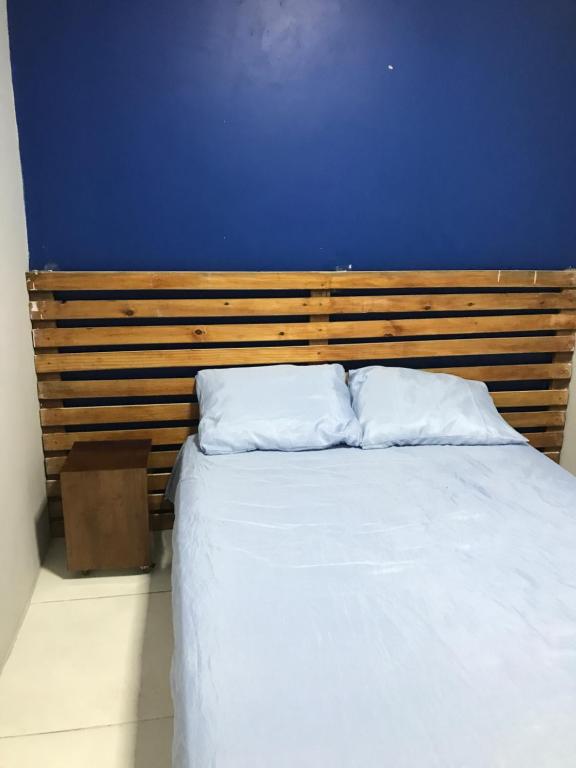 1 cama con pared azul y 2 almohadas blancas en Hostel do Rasta, en Salvador