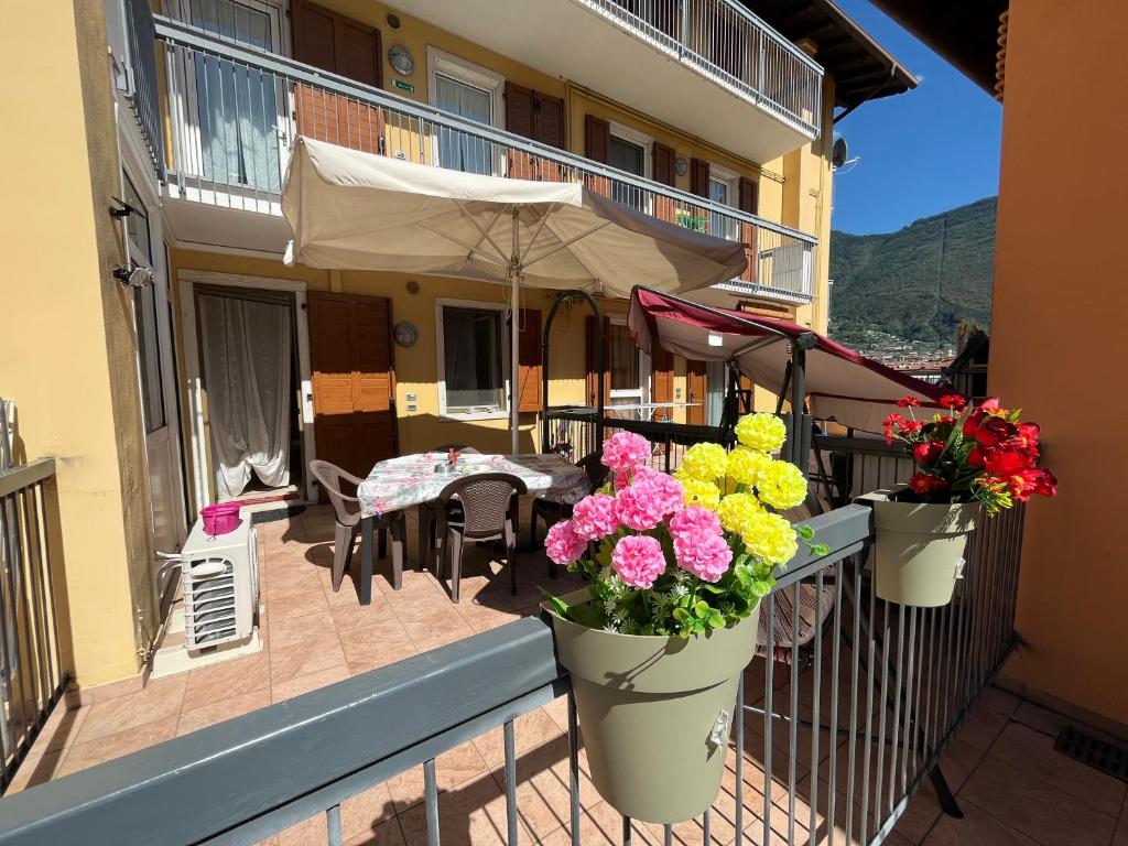 a balcony with a table and flowers in buckets at Appartamento Capri in Arco