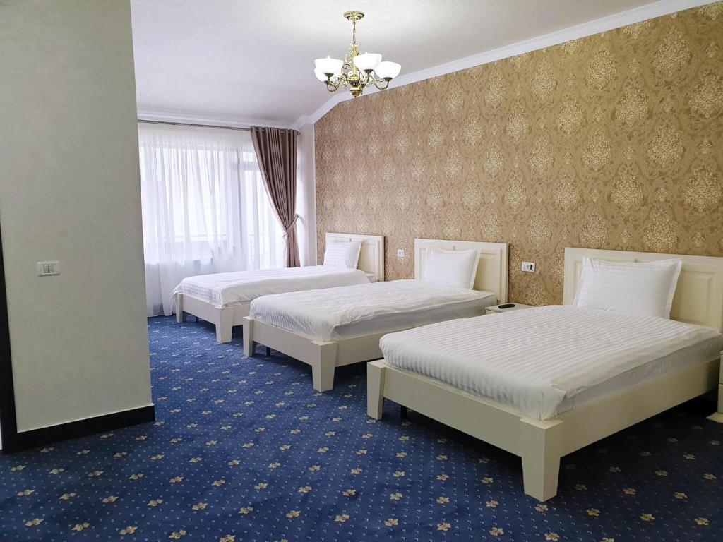 Habitación de hotel con 3 camas y lámpara de araña. en Hotel Bacsoridana en Tecuci
