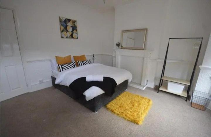 a bedroom with a bed and a yellow rug at CONTRACTORDIGS with FREE parking - excellent road links in Nuneaton