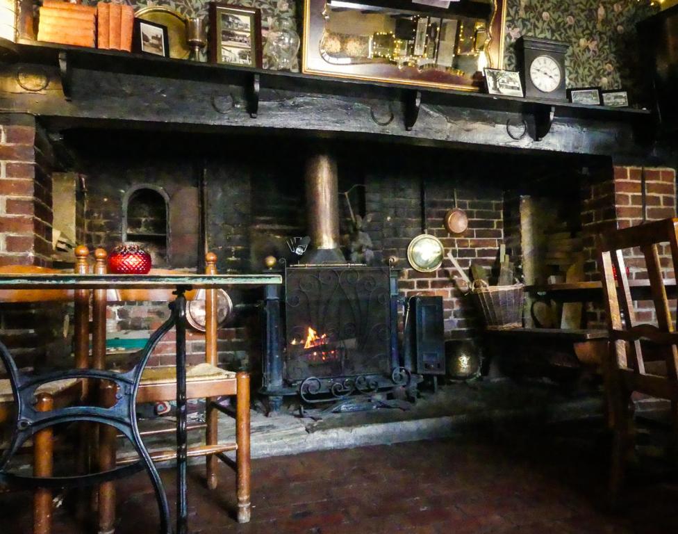 a living room with a fireplace and a table and chair at Ye Olde Smugglers Inne in Alfriston