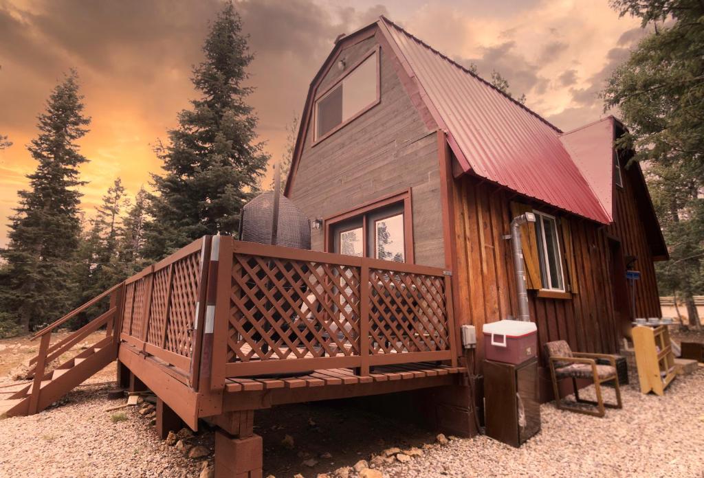 a cabin with a large deck and a red roof at Charming Blue Farmhouse Cabin in Duck Creek Village