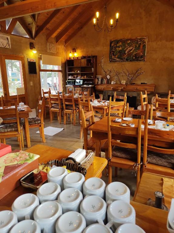 a dining room with white dishes on tables and chairs at Valle Puelo in Lago Puelo