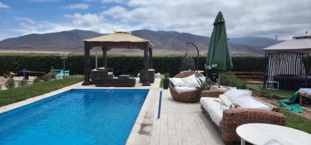 a swimming pool with a gazebo and chairs and a table at MANUIA in Coquimbo