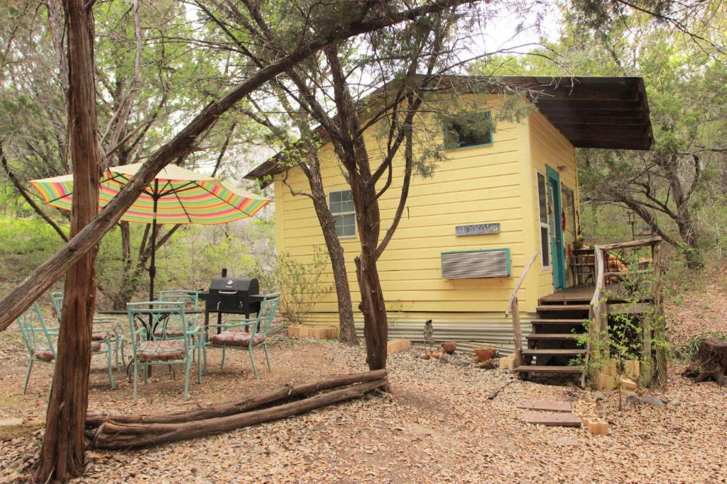 una pequeña casa amarilla con una mesa y una tienda de campaña en The Mexico Cabin at Creekside Camp & Cabins, en Marble Falls