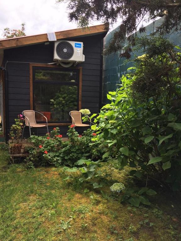 a house with two chairs and a window with a fan at TINY HOUSE EL ROBLE in Puerto Varas