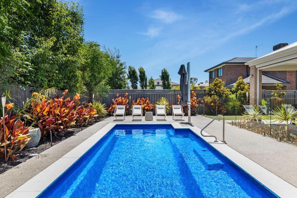 a swimming pool in a yard with chairs and plants at The Witton Holiday House in Yarrawonga