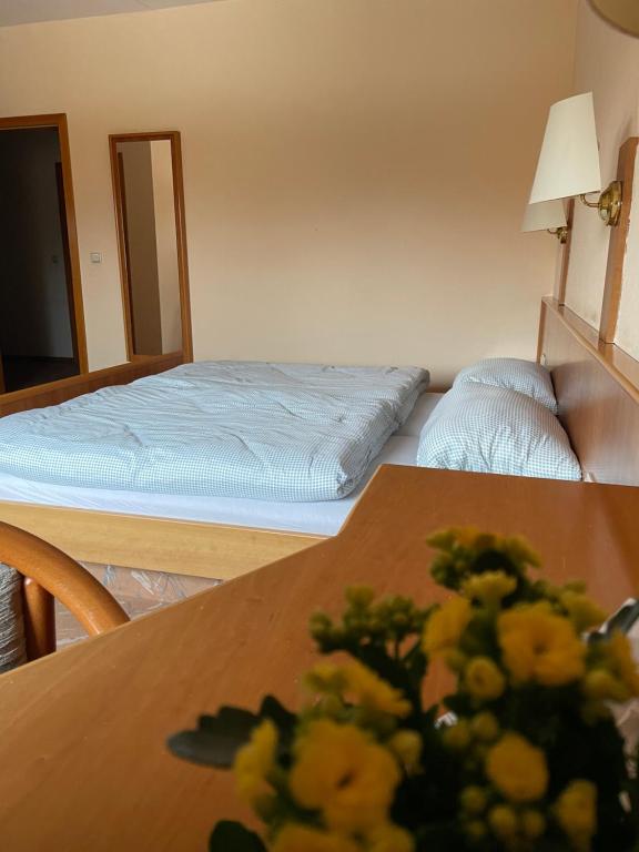 a bedroom with a bed and a table with flowers on it at Gasthaus Neue Mühle in Westhausen