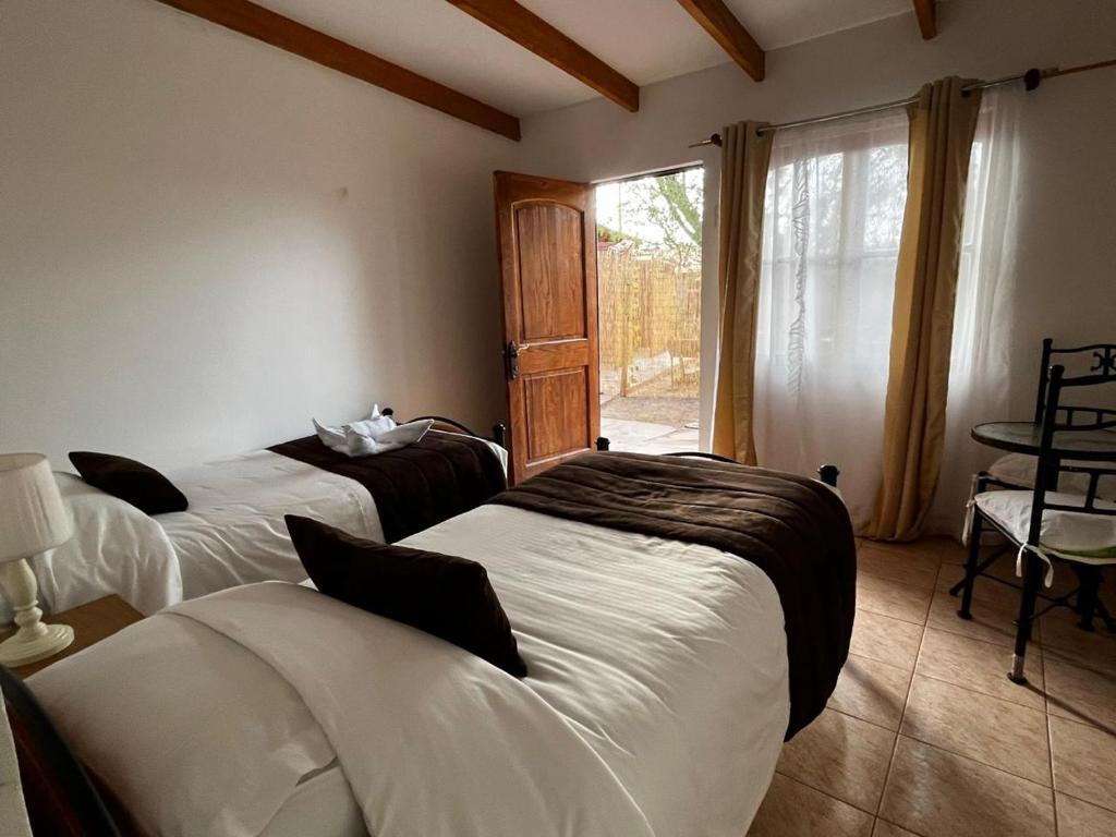 a bedroom with two beds and a window at Hostal Katarpe in San Pedro de Atacama