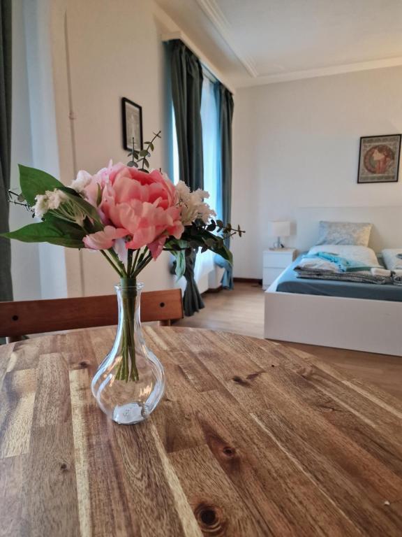 wazon kwiatów siedzący na stole w pokoju w obiekcie Bastis City Rooms w Lucernie