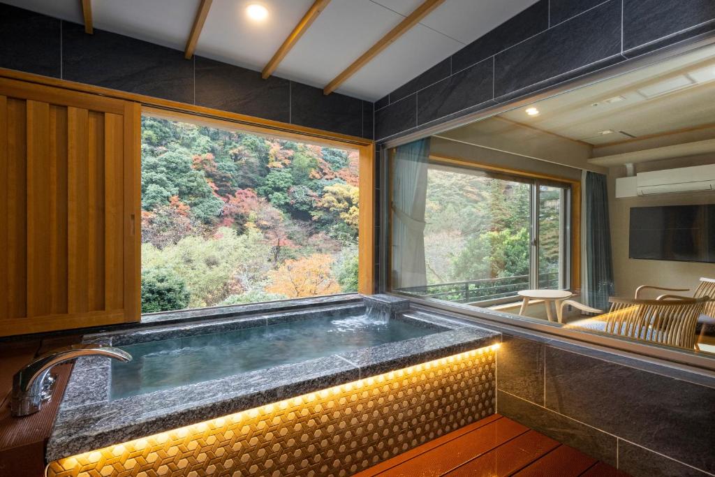 a large tub in a room with a large window at Hotel Okada in Hakone