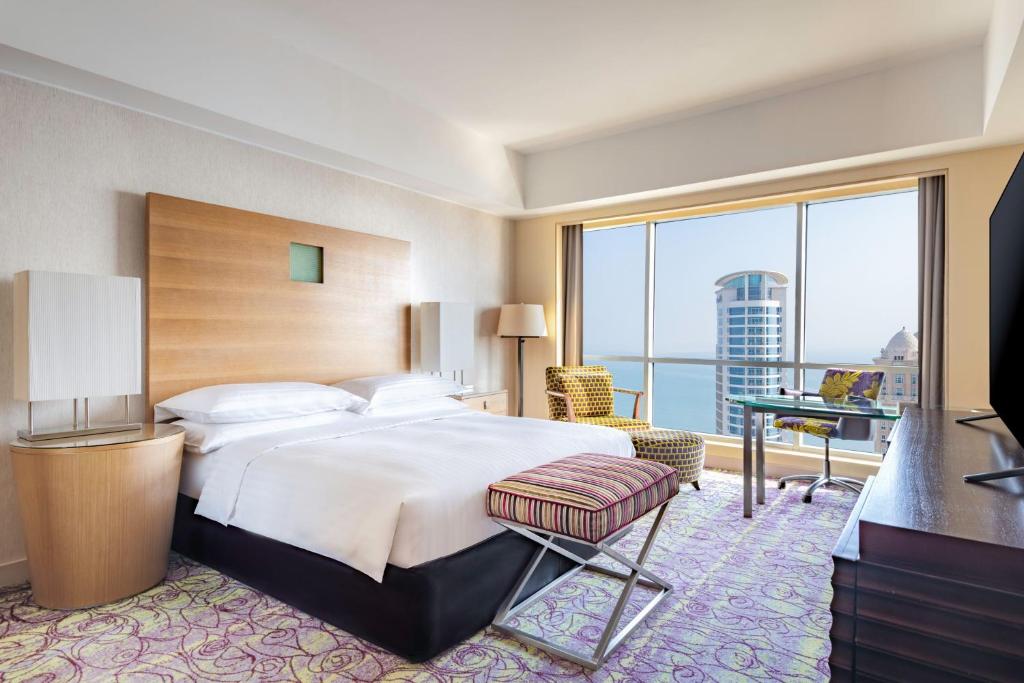 a hotel room with a bed and a large window at Qabila Westbay Hotel in Doha