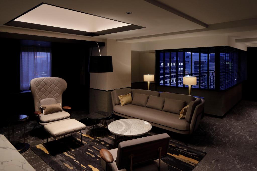 a living room with a couch and two chairs at Cross Hotel Osaka in Osaka