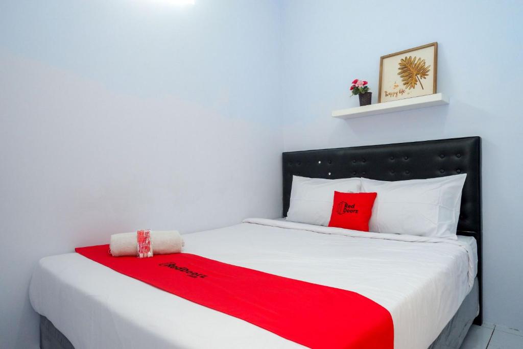 um quarto com uma cama com um cobertor vermelho em RedDoorz near Puri Anjasmoro Area Semarang em Semarang