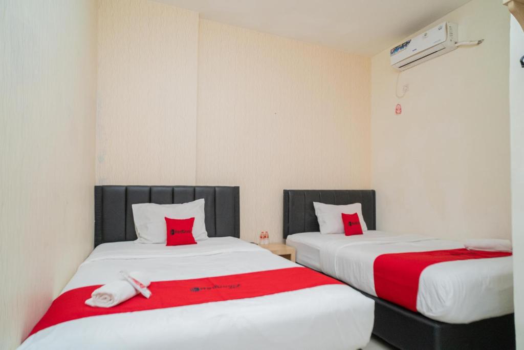 two beds in a room with red and white sheets at RedDoorz near Flyover Arjosari Malang in Malang