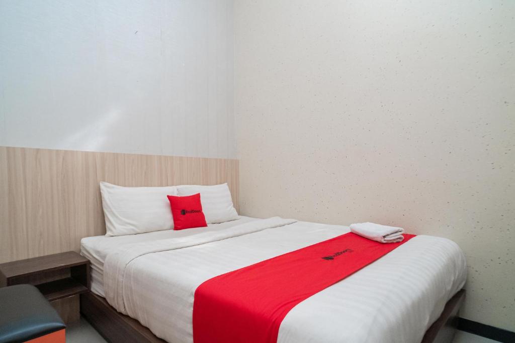 Un dormitorio con una cama con una manta roja. en RedDoorz near Matahari Singosaren Solo, en Solo