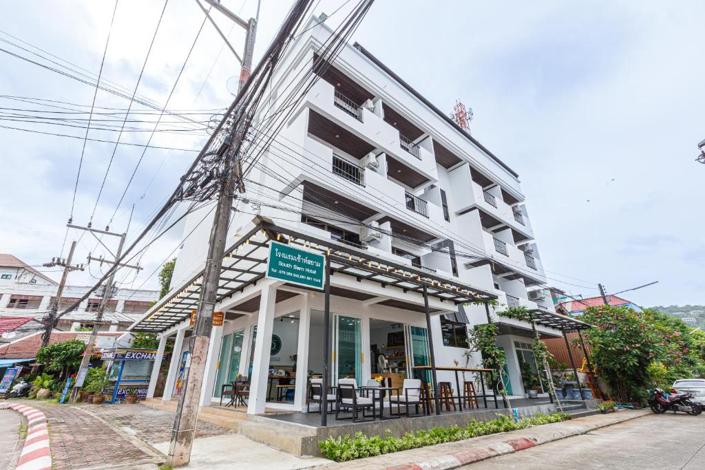 um edifício branco com um restaurante numa rua em South Siam Hotel em Cidade Phuket