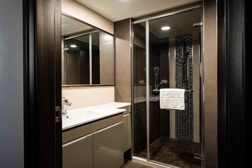 a bathroom with a glass shower and a sink at Global Traveler Hotel in Kaohsiung