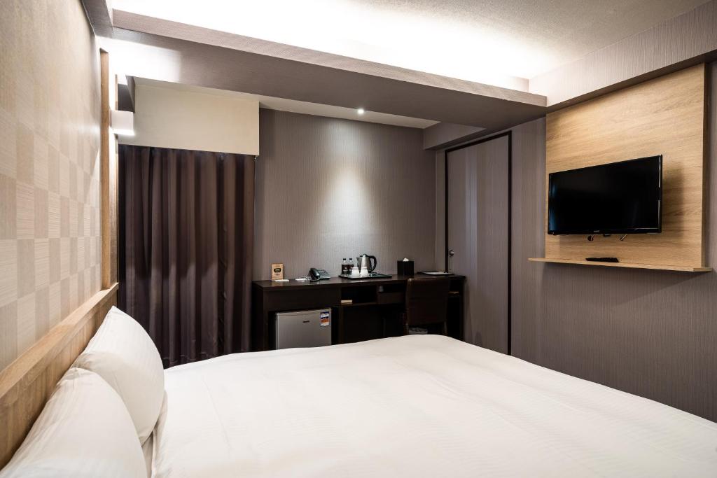 a hotel room with a bed and a flat screen tv at Global Traveler Hotel in Kaohsiung