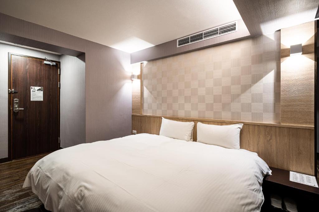 a bedroom with a large white bed and a door at Global Traveler Hotel in Kaohsiung