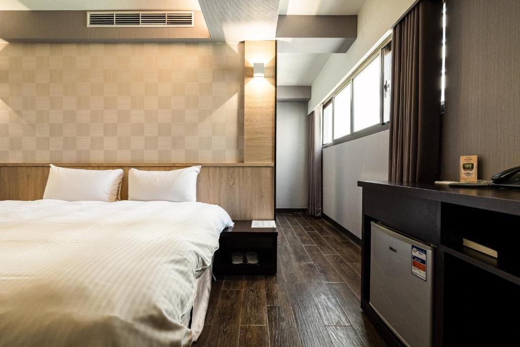 a hotel room with a large bed and a window at Global Traveler Hotel in Kaohsiung
