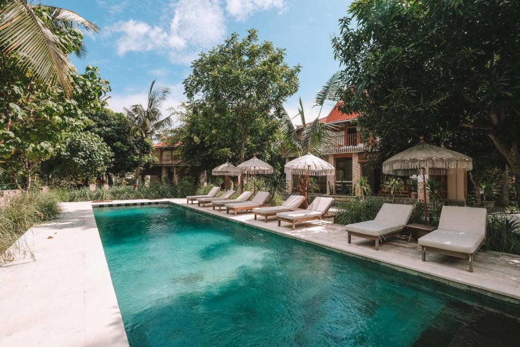 einen Pool mit Stühlen und Sonnenschirmen neben einem Haus in der Unterkunft Diamond Beach Villas in Nusa Penida