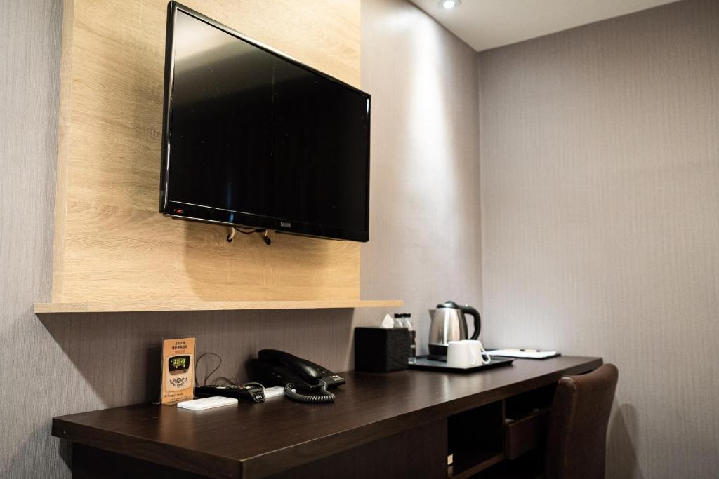 a hotel room with a desk with a television on a wall at Global Traveler Hotel in Kaohsiung