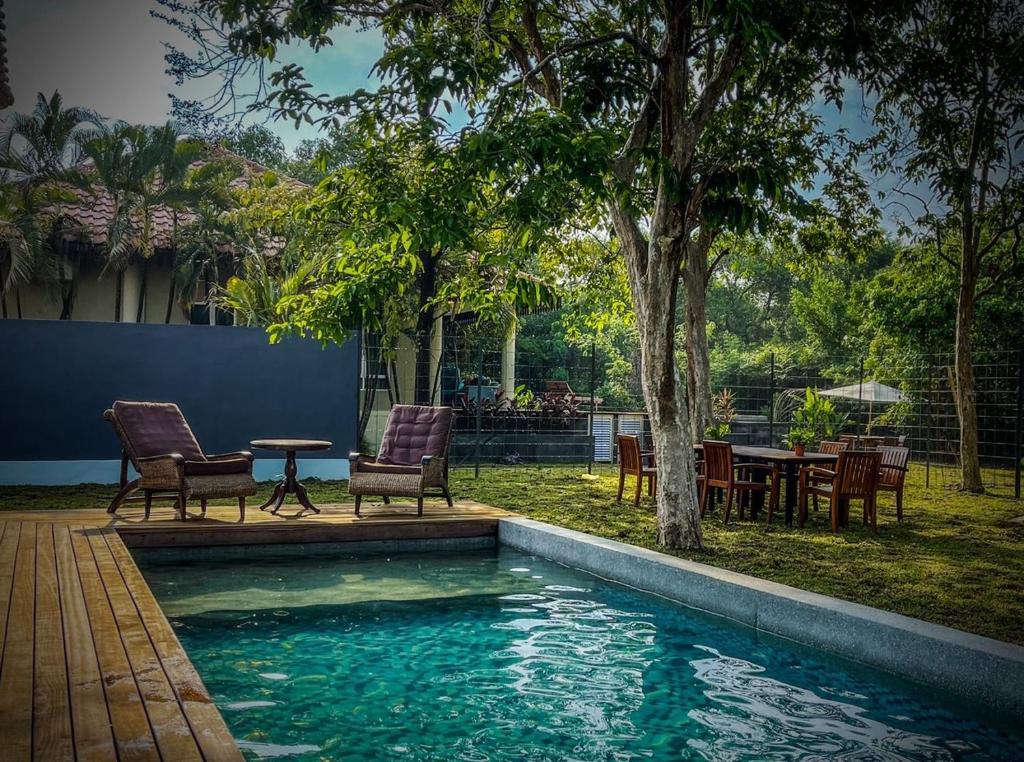 a swimming pool with chairs and a table in a yard at Royale Riviera Resort Private Pool Villas in Pantai Cenang