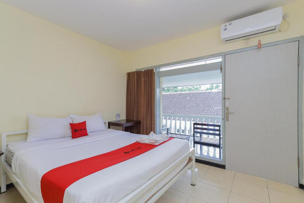 a bedroom with a large bed and a balcony at RedDoorz at CBR Residence Blimbing in Malang