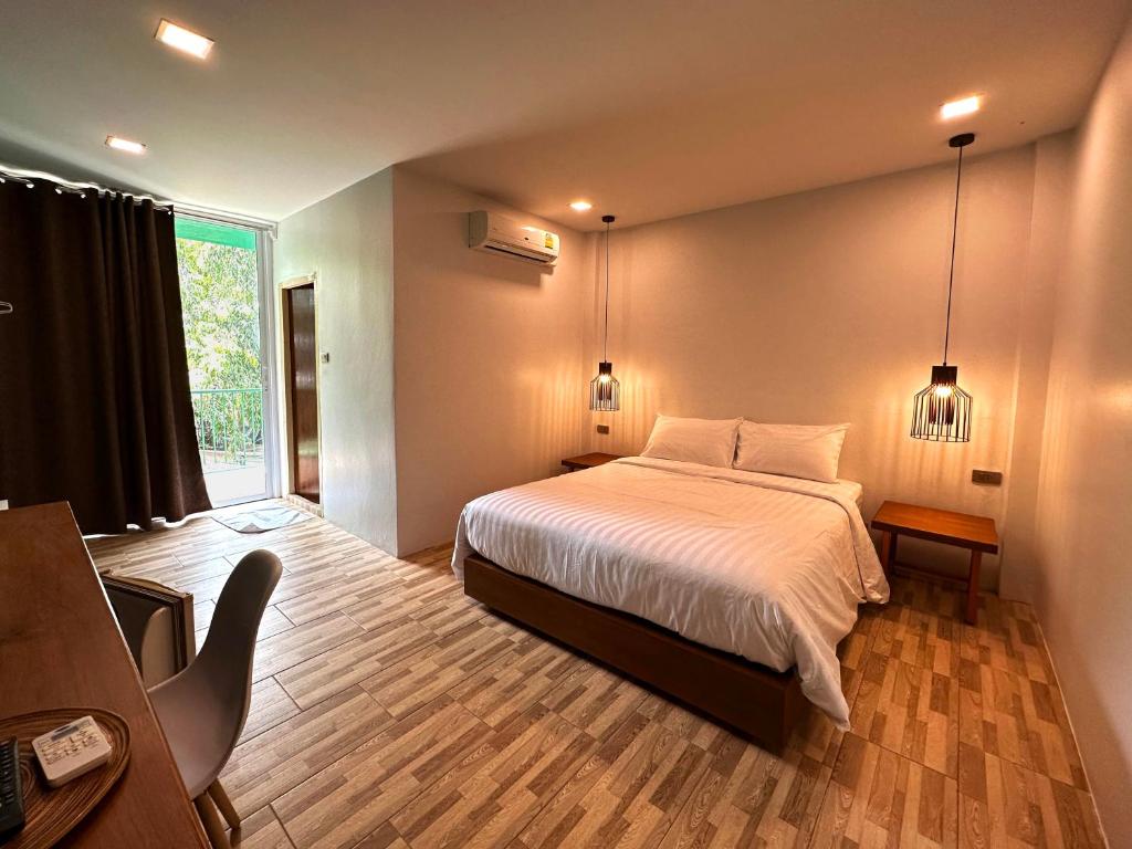 a bedroom with a bed and a large window at Plernpetch Hotel in Surat Thani