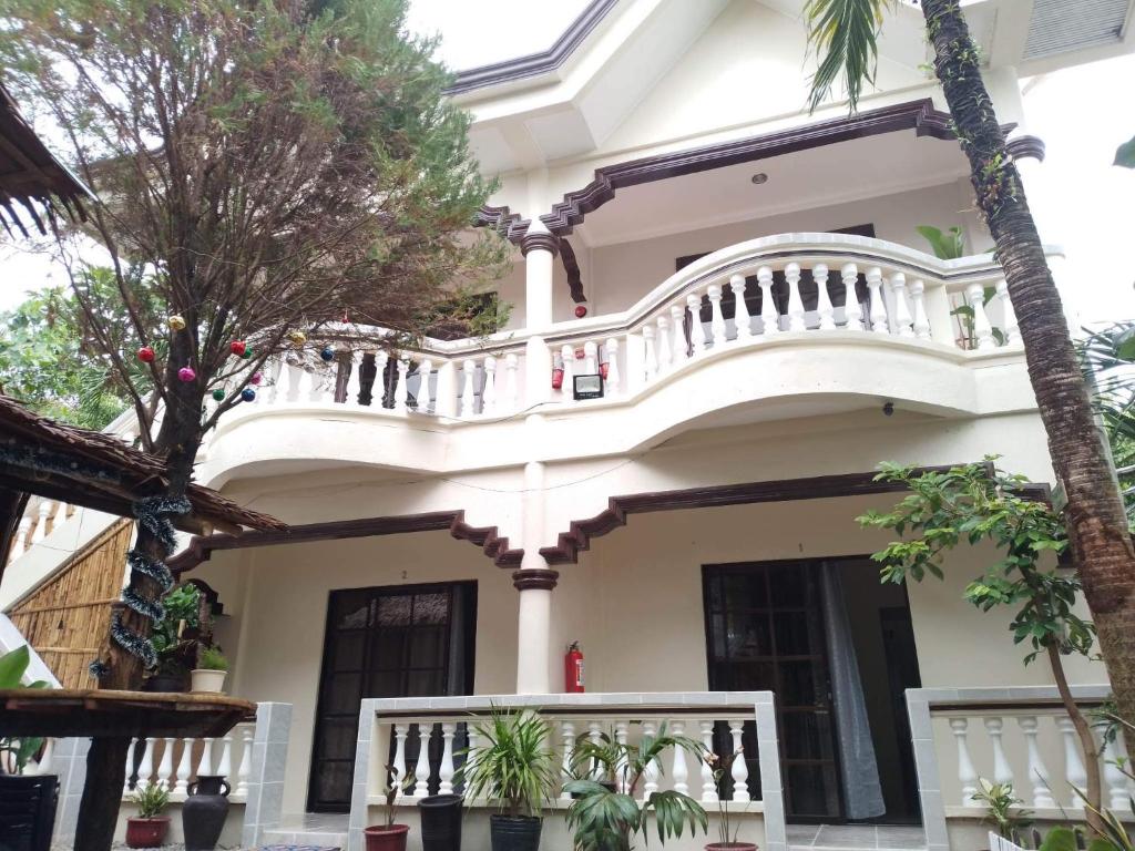 a white house with a balcony and palm trees at Tresha Lance Apartelle in Boracay