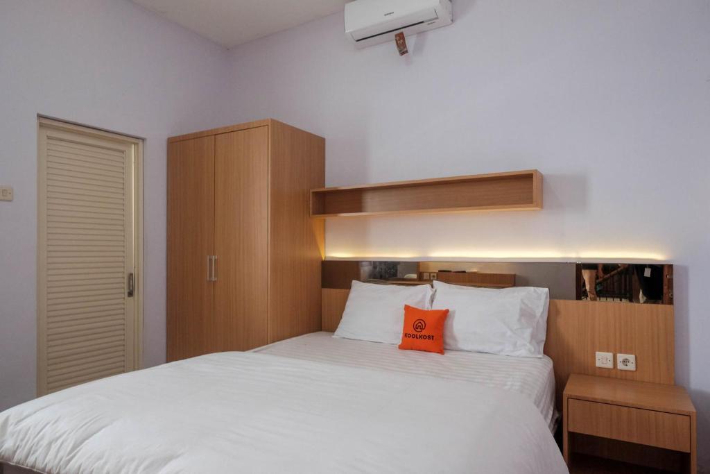 - une chambre avec un grand lit blanc et un oreiller orange dans l'établissement KoolKost Syariah near Taman Sriwedari Laweyan, à Solo