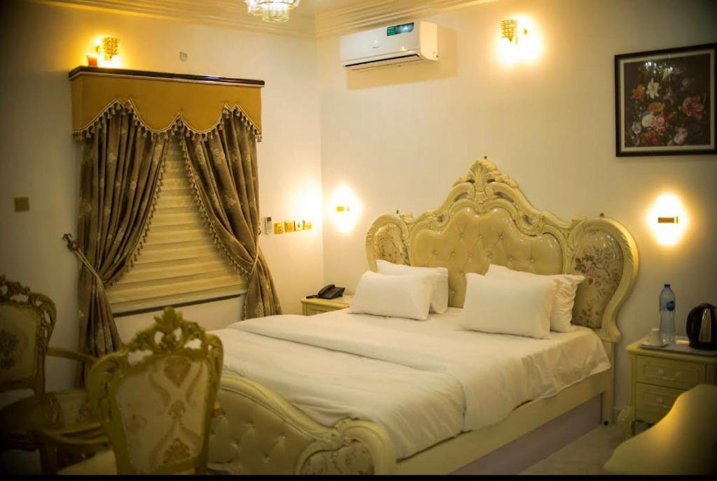 ein Schlafzimmer mit einem weißen Bett und einem Stuhl in der Unterkunft Kawruky Hotel Guobadia in Benin-Stadt