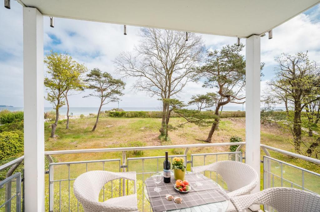 een tafel en stoelen op een veranda met uitzicht op de oceaan bij Meerstern in Juliusruh