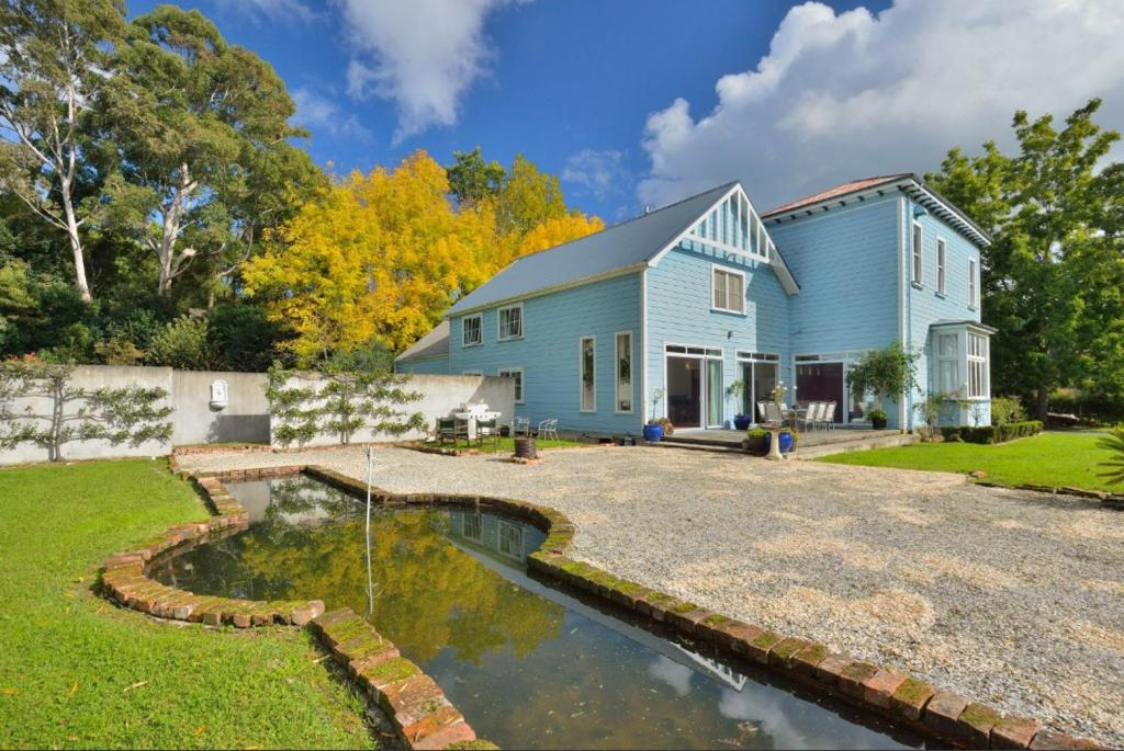 a blue house with a pond in front of it at The Gisborne Club - Boutique accommodation in Gisborne