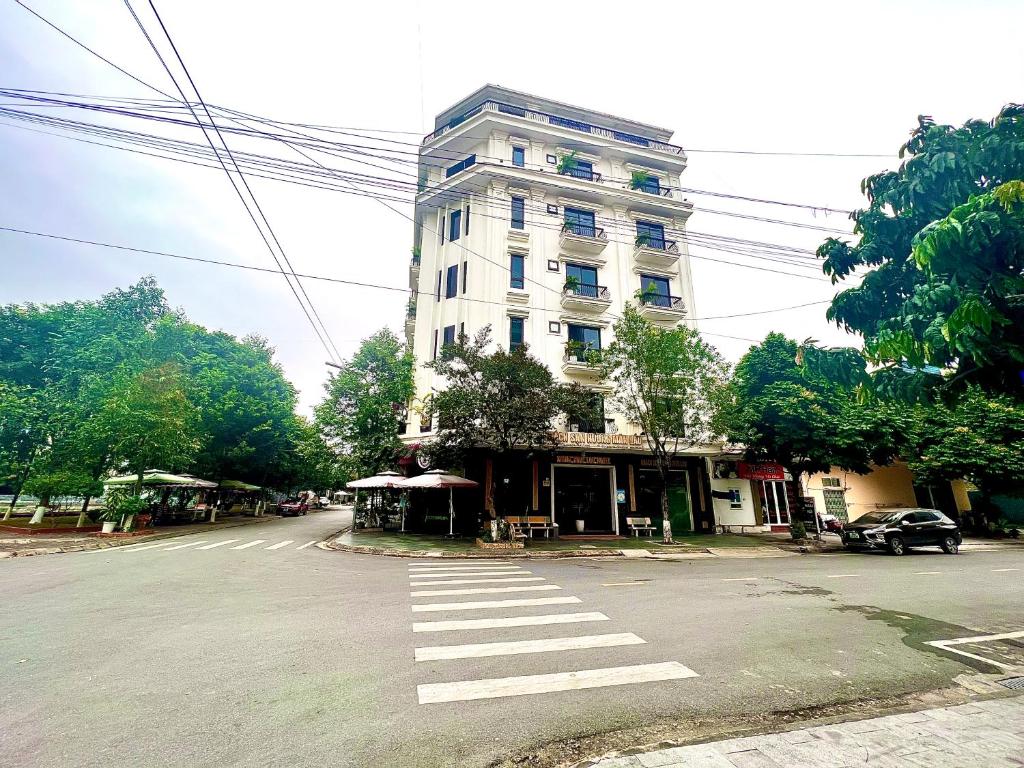 a large white building on a street with a crosswalk at Khách sạn Hương mãn Lầu in Bắc Ninh