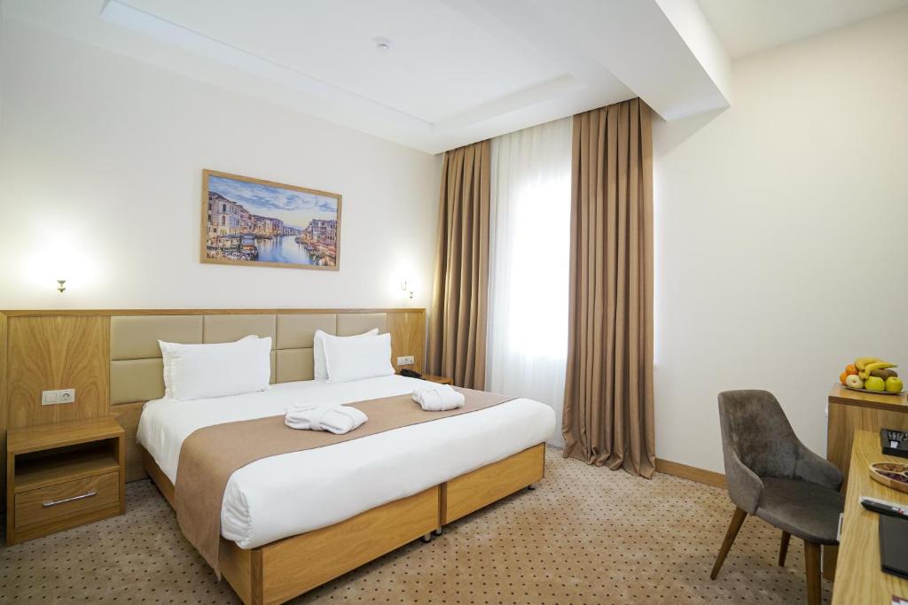 a hotel room with a large bed and a desk at Milan Hotel in Tashkent