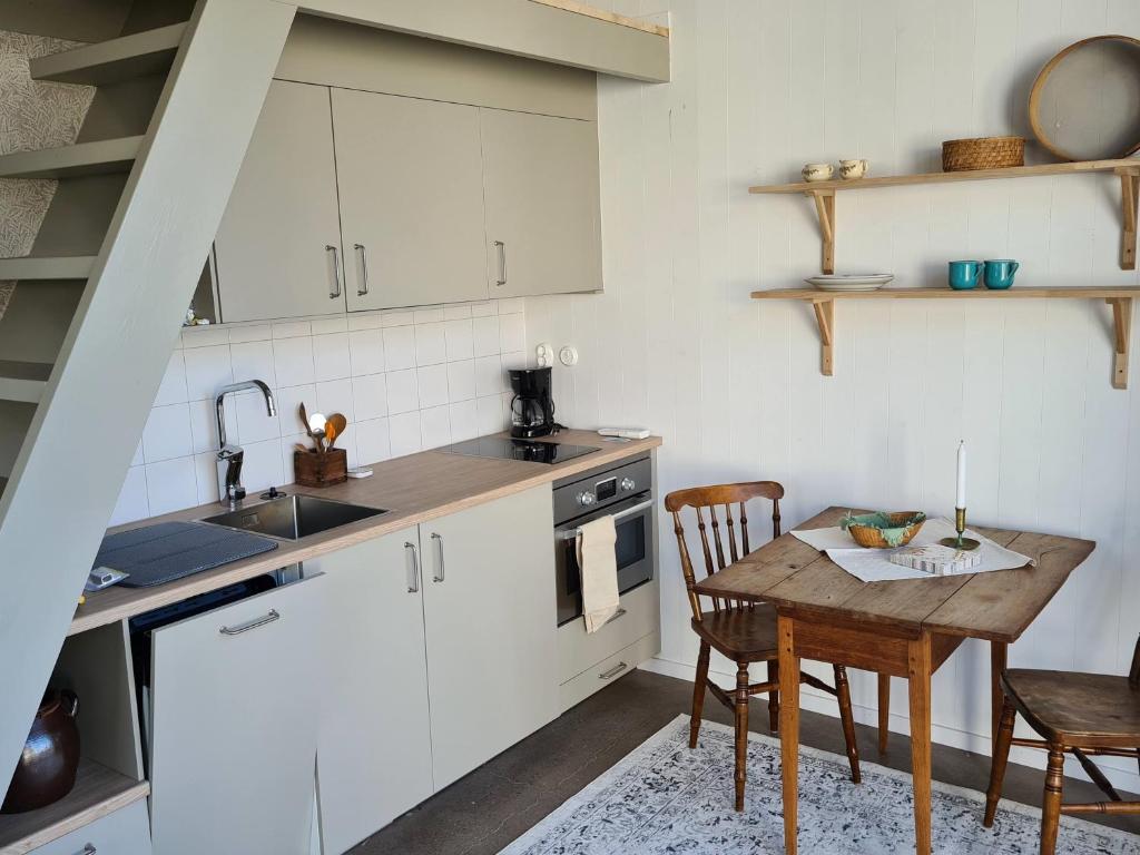 cocina con armarios blancos y mesa de madera en Minihuset nära havet en Varberg