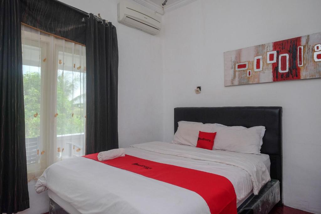 1 dormitorio con 1 cama con manta roja en RedDoorz at Paris Ocean, en Yogyakarta