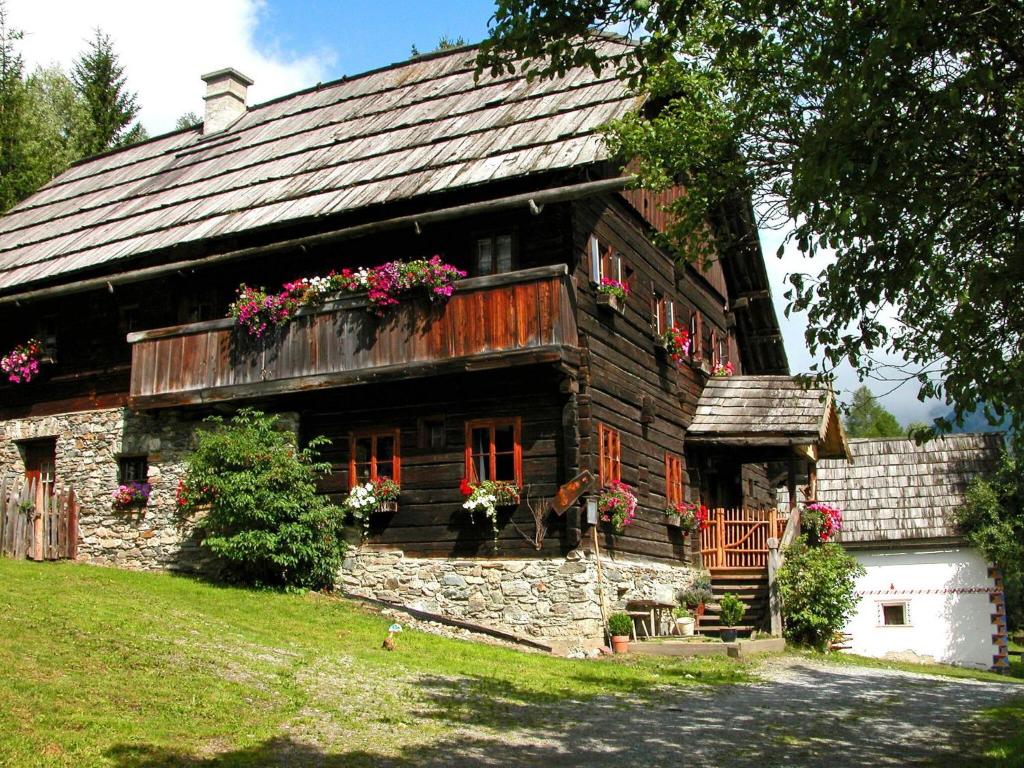 una vecchia casa in legno con fiori alle finestre di Holiday home Mesnerhaus Fuchsn, Weisspriach im Lungau a Weisspriach