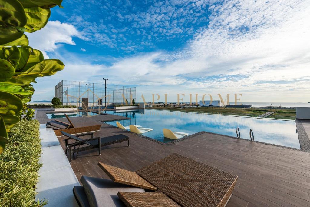 a pool with tables and chairs next to a building at Amber Cove Premier Suites Melaka in Melaka