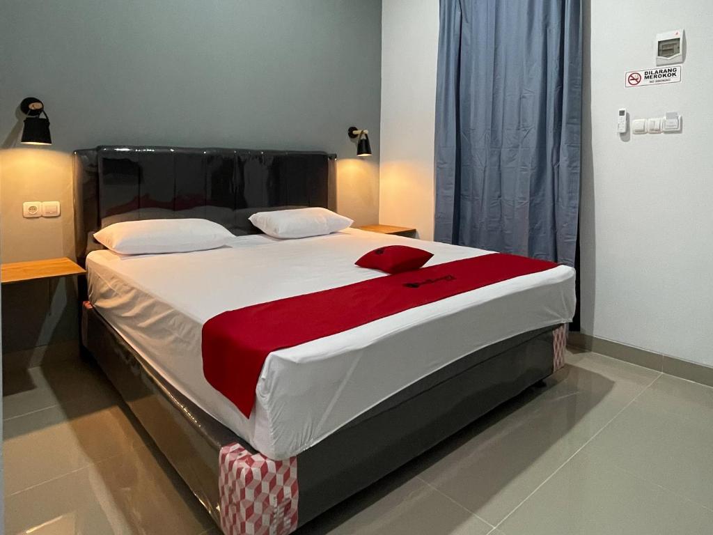 een slaapkamer met een groot bed en een rode deken bij RedDoorz Plus near Alun Alun Kota Bora in Blora