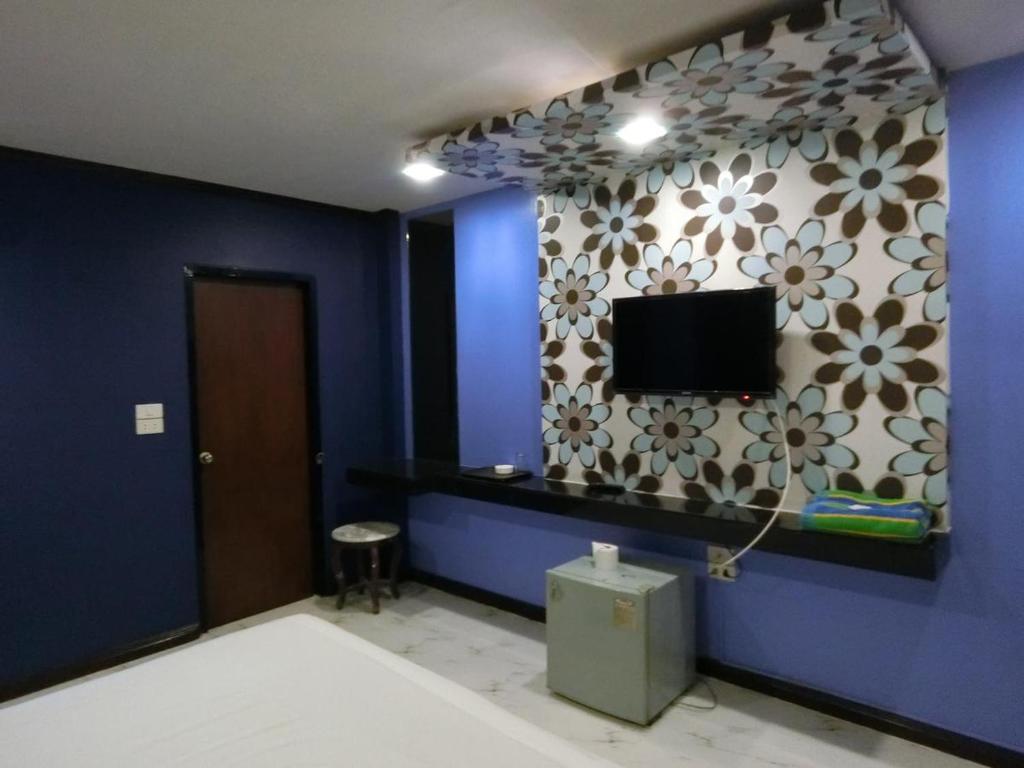 um quarto com uma parede azul com uma televisão em NewYork Suite Hotel em Ban Ko
